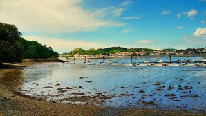 A coastal town with boats docked along the shore, a sandy beach, and a backdrop of hills and buildings. - YHA Conwy - Hostel (Conwy)