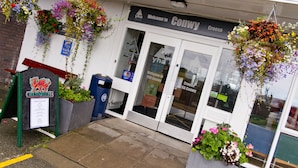 A storefront with hanging flower baskets, a sign reading "Welcome to Conwy," and a "Croeso" sign. - YHA Conwy - Hostel (Conwy)