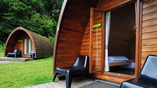 A wooden cabin with a bed and two chairs outside. - YHA Hawkshead - Hostel (Ambleside)