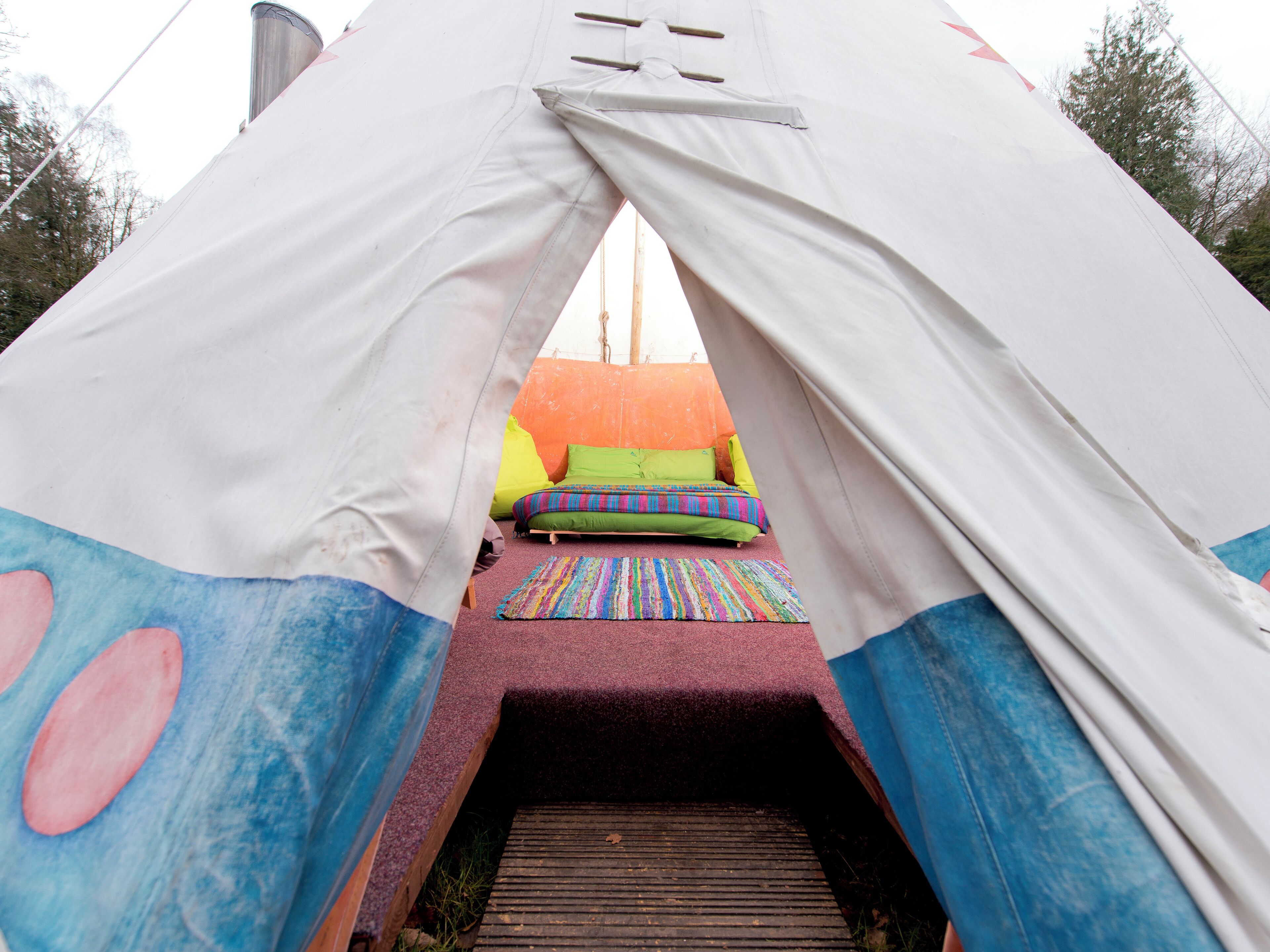 A tent with a colorful interior, including a bed with pillows and a striped rug.