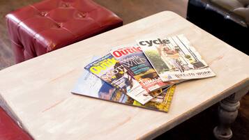 Una mesa de madera con revistas y un otoman de cuero rojo.