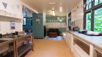 A kitchen with a sink, stove, and microwave. There is a window with a view of greenery outside.