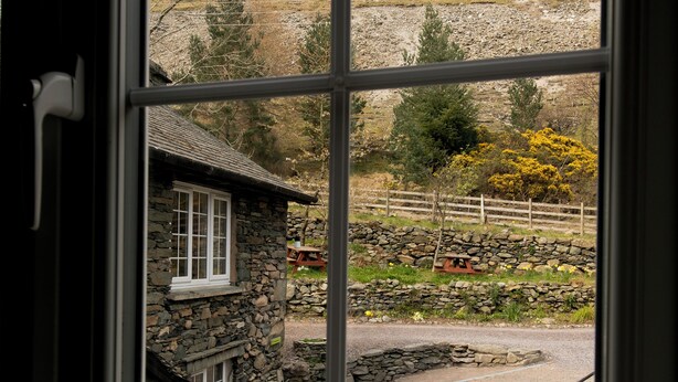 Une petite maison en pierre offrant une vue sur un mur de pierres, une clôture en bois et une table de pique-nique.