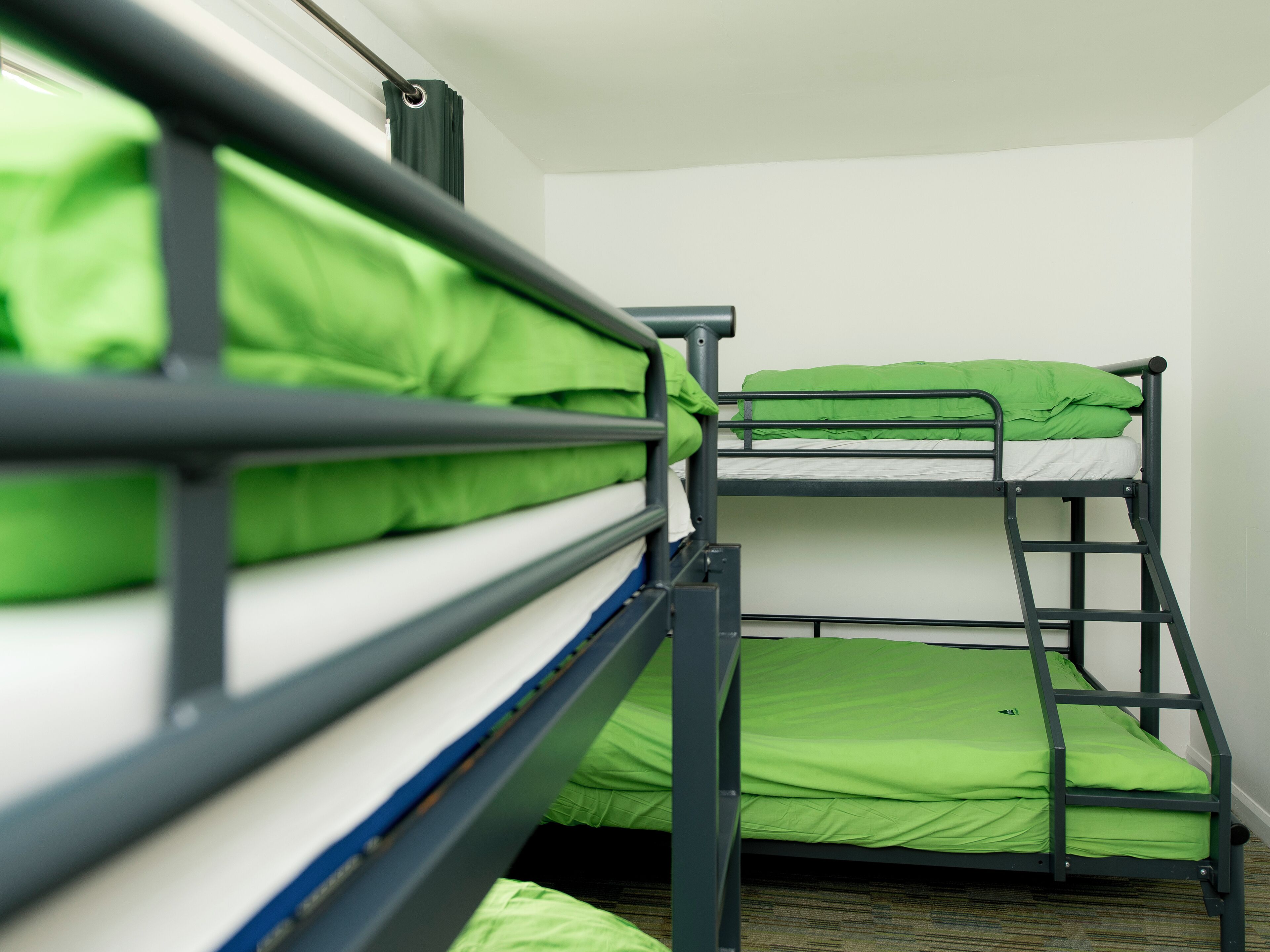 A bunk bed with green bedding in a room with white walls.