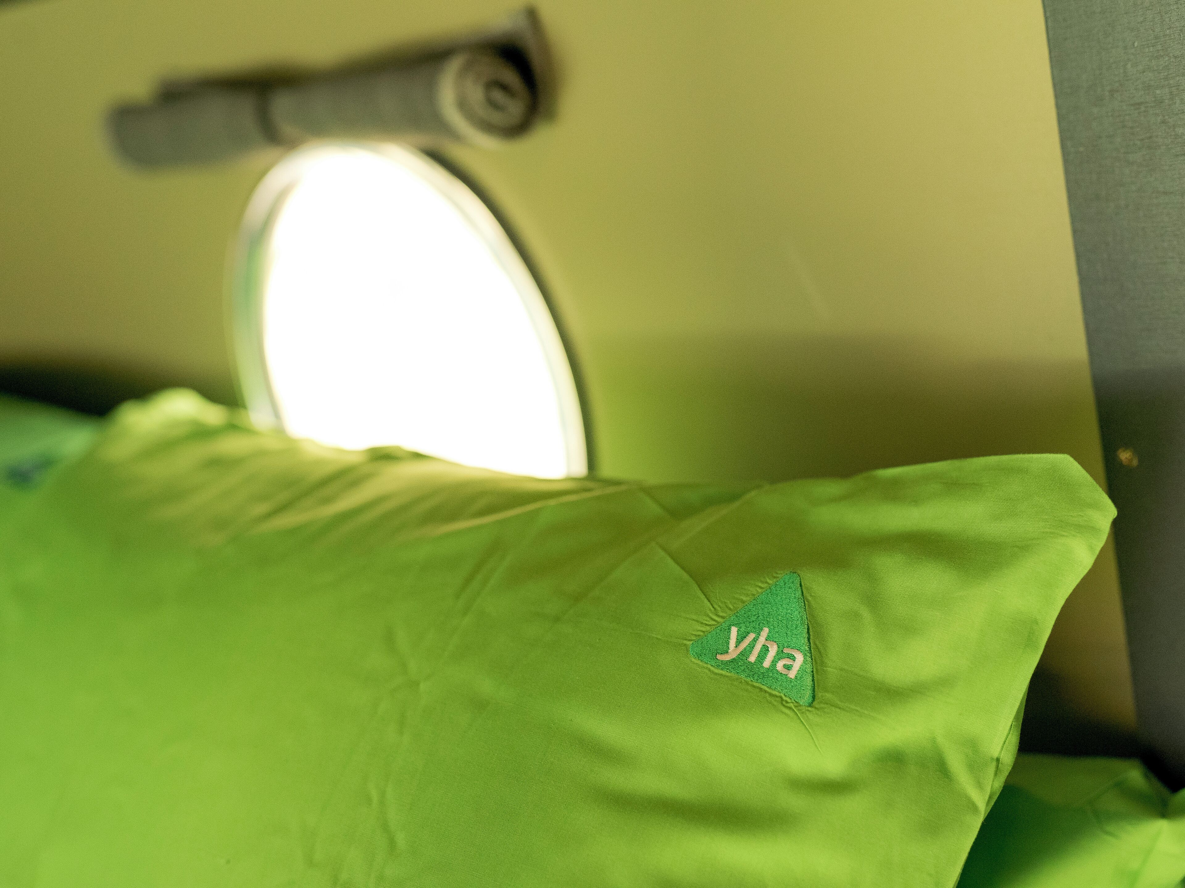A close-up of a green pillow with a logo, a circular light fixture, and a metallic handle.