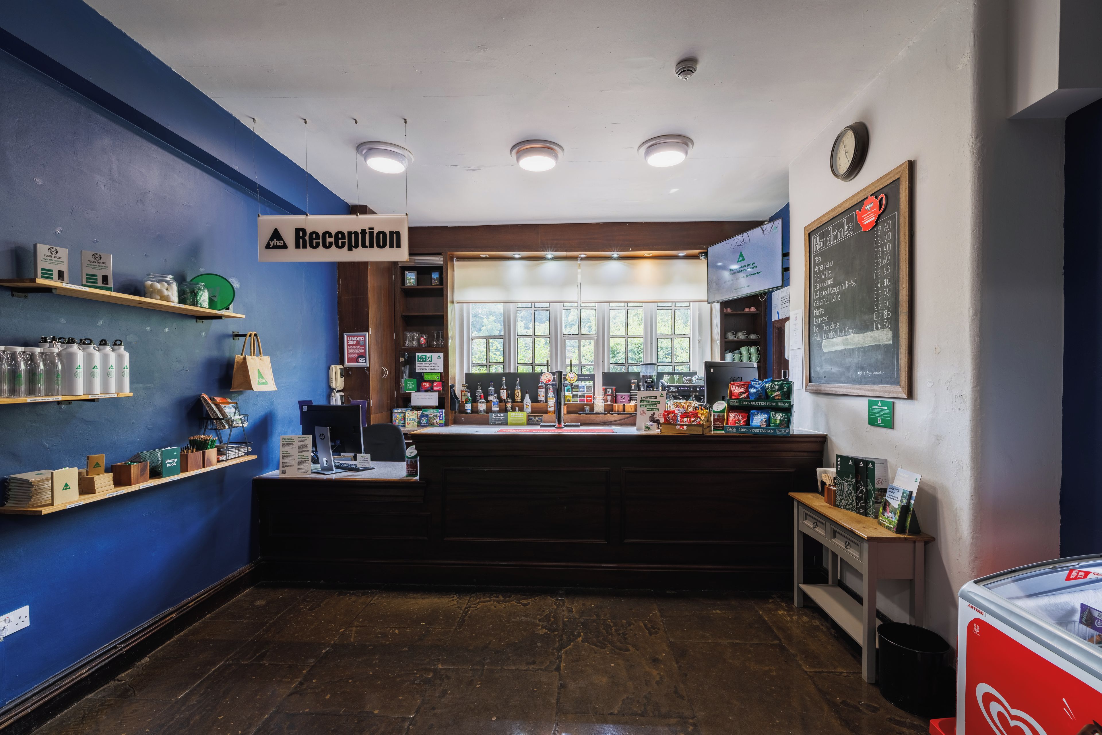 A reception area with a blue wall, a reception desk, a chalkboard menu, and a clock on the wall.