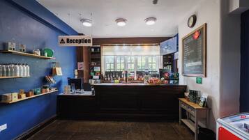 A reception area with a blue wall, a reception desk, a chalkboard menu, and a clock on the wall.