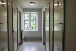 A corridor with doors on both sides, a window at the end, and a radiator on the wall.