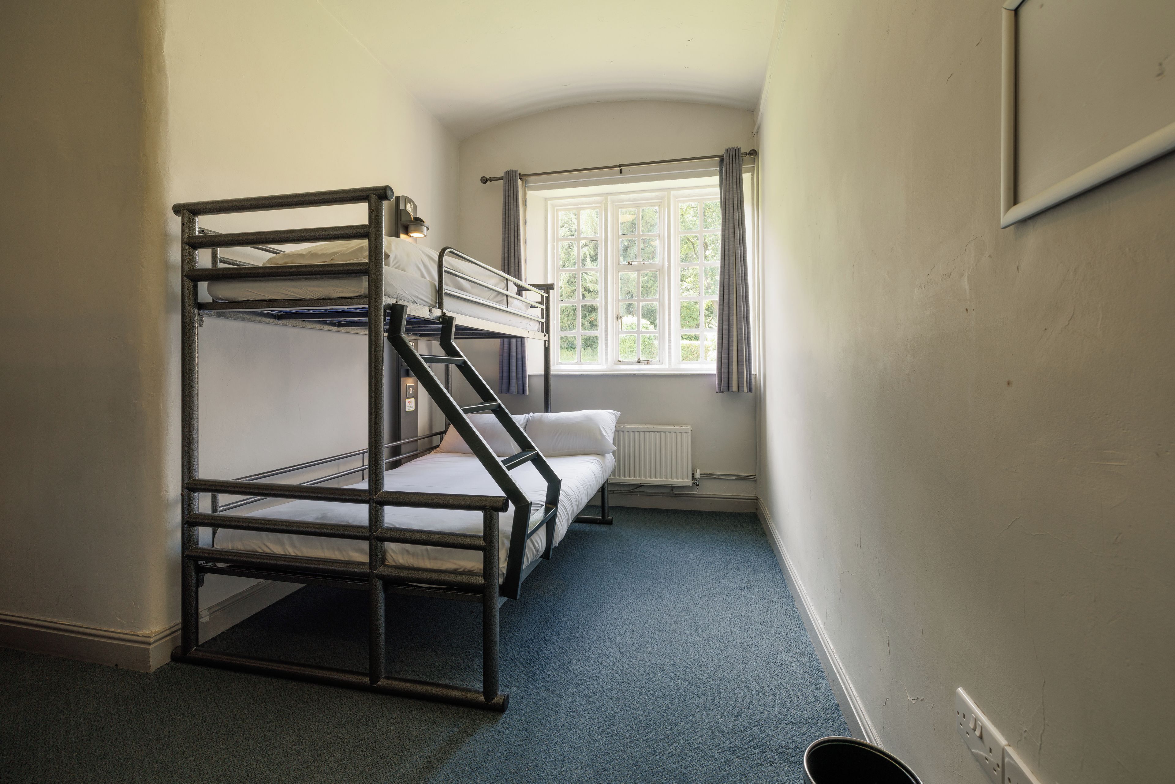 A bunk bed room with a window and a radiator.