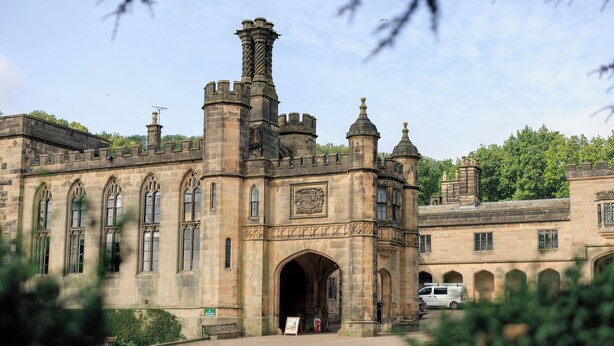 A historic building with a large arched entrance, multiple windows, and a flagpole. - YHA Ilam Hall - Hostel (Ashbourne)