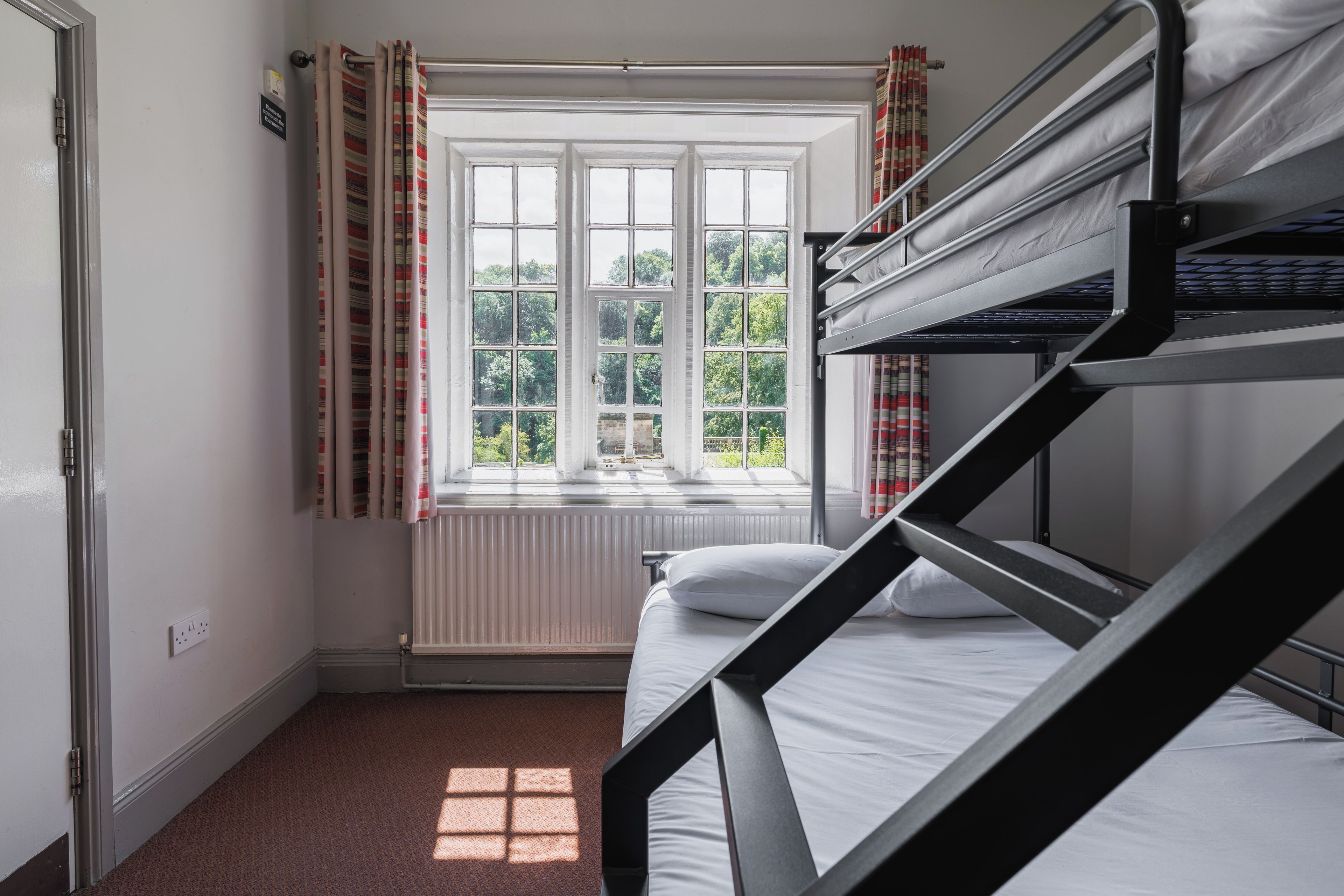 A bunk bed room with a window and curtains.