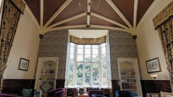 A room with a high ceiling, patterned wallpaper, a bay window, and a chandelier.