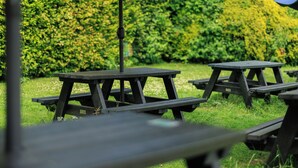 Outdoor picnic tables with a green hedge in the background. - YHA Ilam Hall - Hostel (Ashbourne)