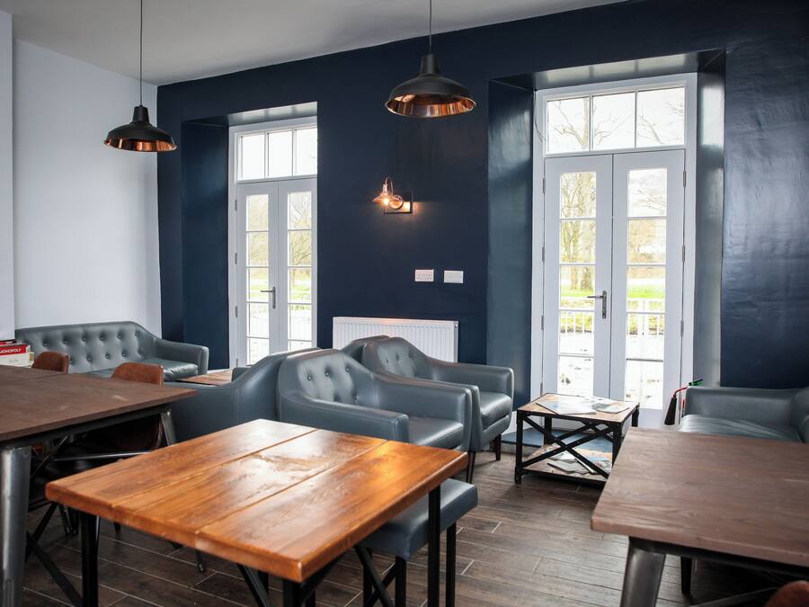 A modern dining area with dark blue walls, large windows, and leather seating.