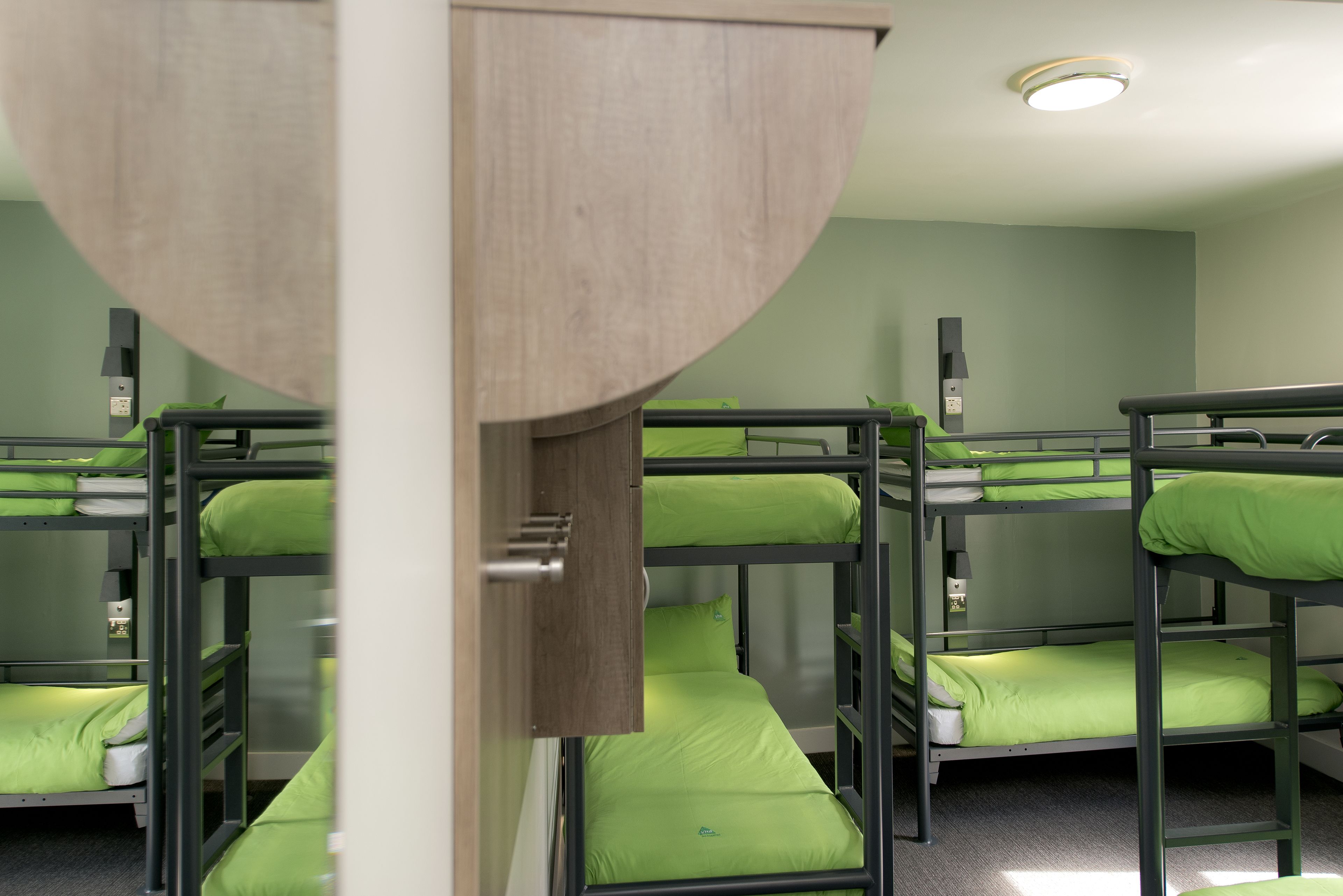 Un dormitorio con literas, un armario de madera y una lámpara en el techo.
