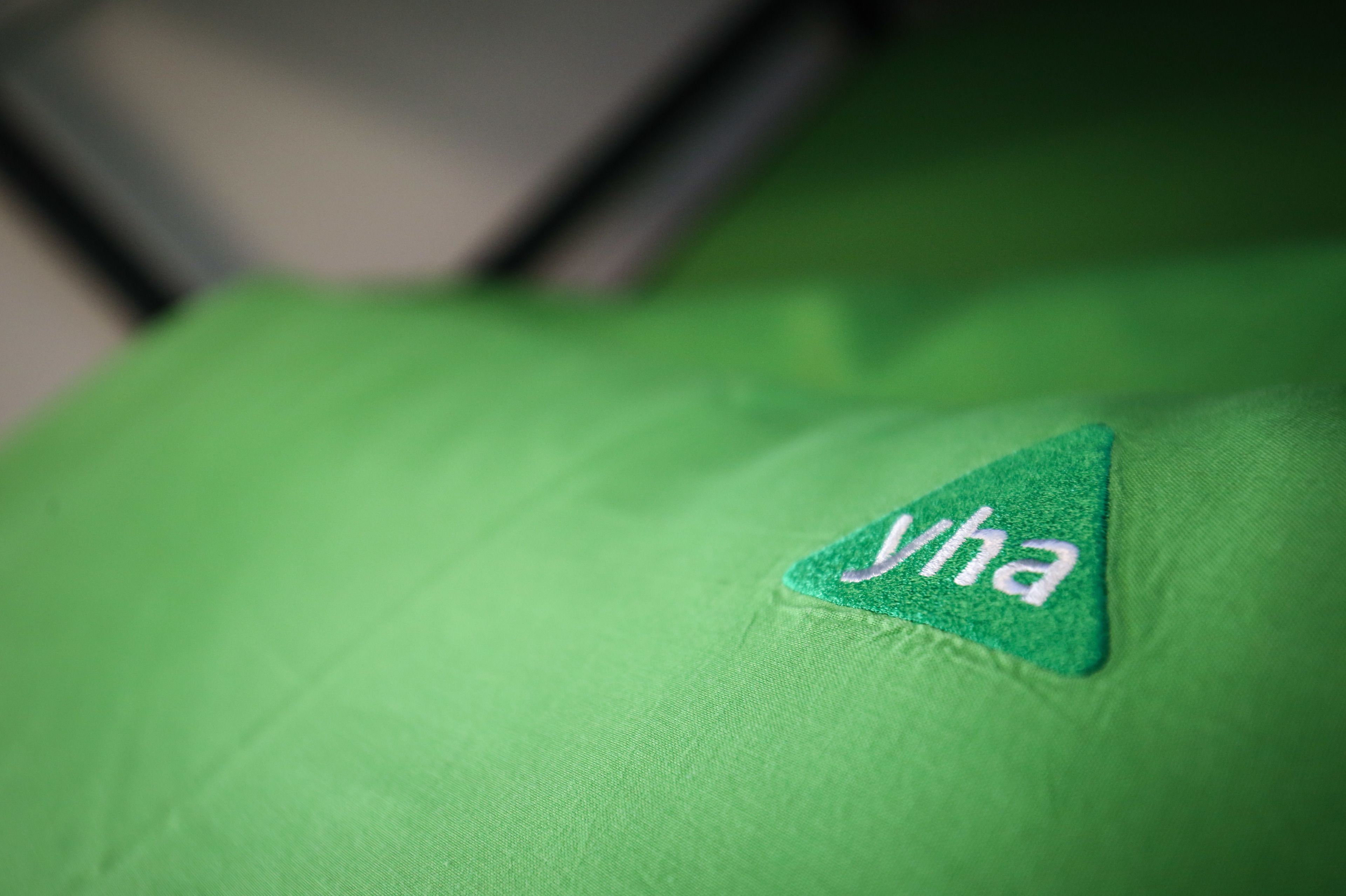 A close-up of a green fabric with a triangular patch featuring the text "yha".