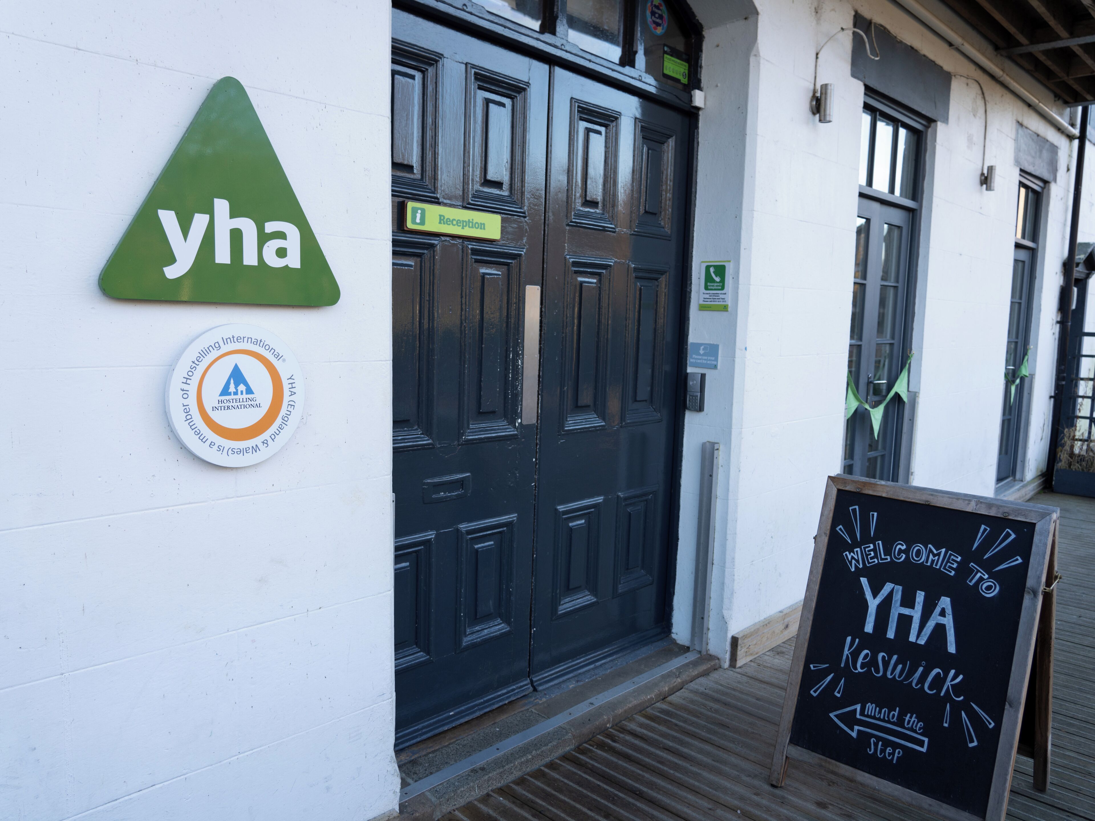 A reception sign, a logo, and a welcome sign for YHA Keswick.