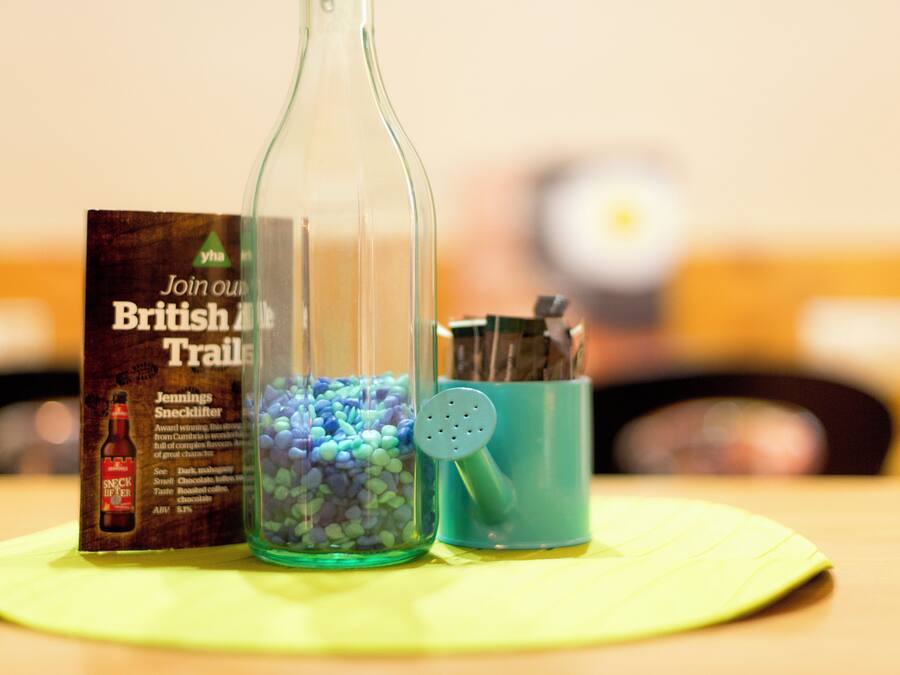 Une bouteille en verre, un petit récipient contenant des petits cailloux bleus et une affiche publicitaire pour le produit Jennings' Snicklifter, le tout posé sur un set de table jaune.
