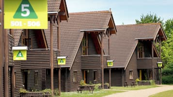 A row of log cabins with numbered signs indicating room numbers and contact numbers.
