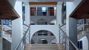 A staircase with metal railings, stone steps, and a view of upper floors with windows and doors. - Pemicsa Hotel (Accra)