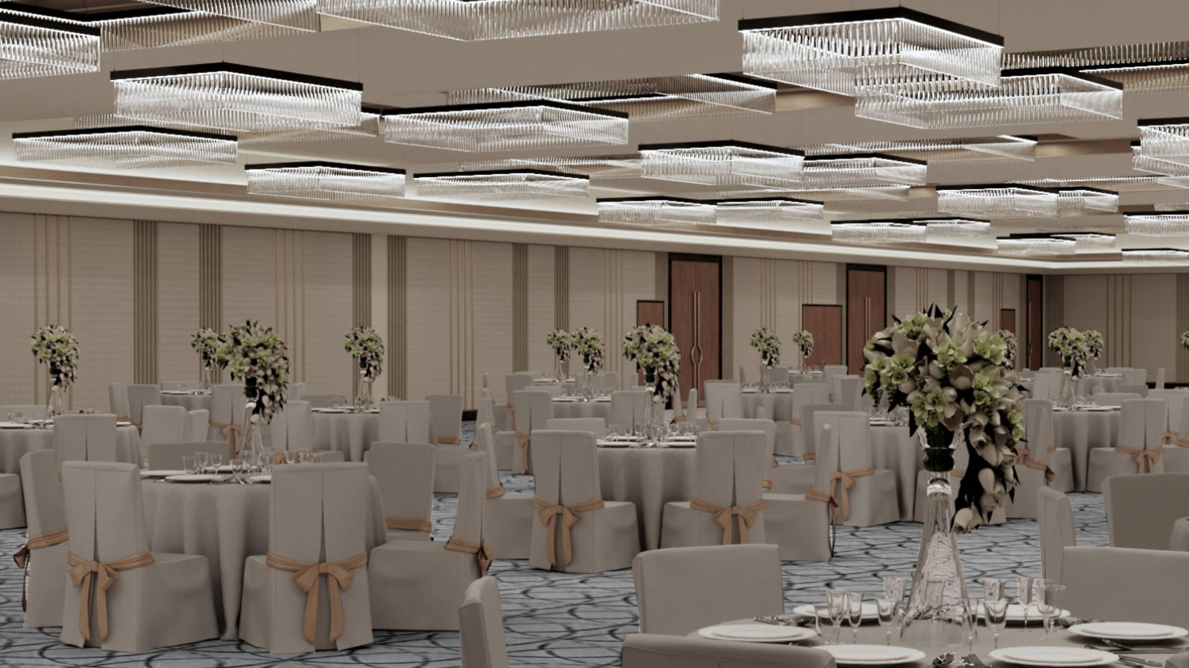 A banquet hall with round tables, chairs, and floral centerpieces.