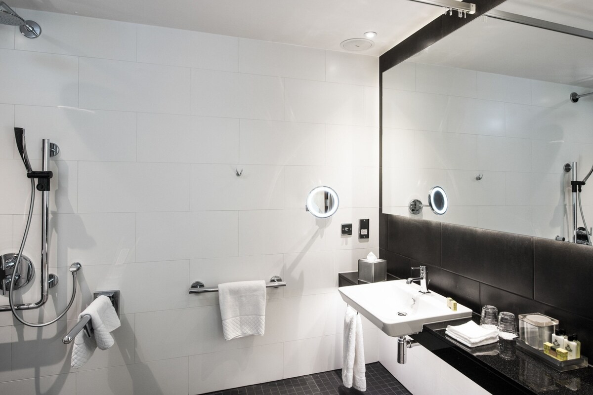 A modern bathroom with a shower, a sink, a mirror, and a towel rack.