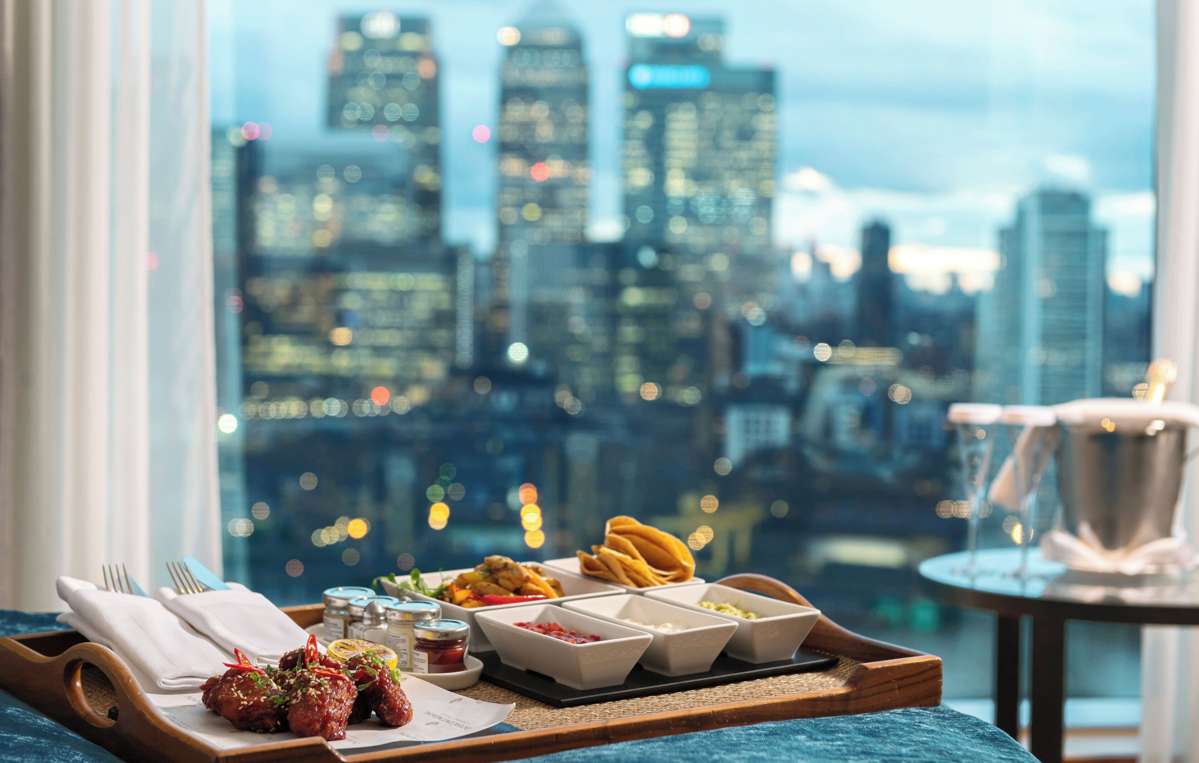 A meal tray with food and condiments on a table with a city view.