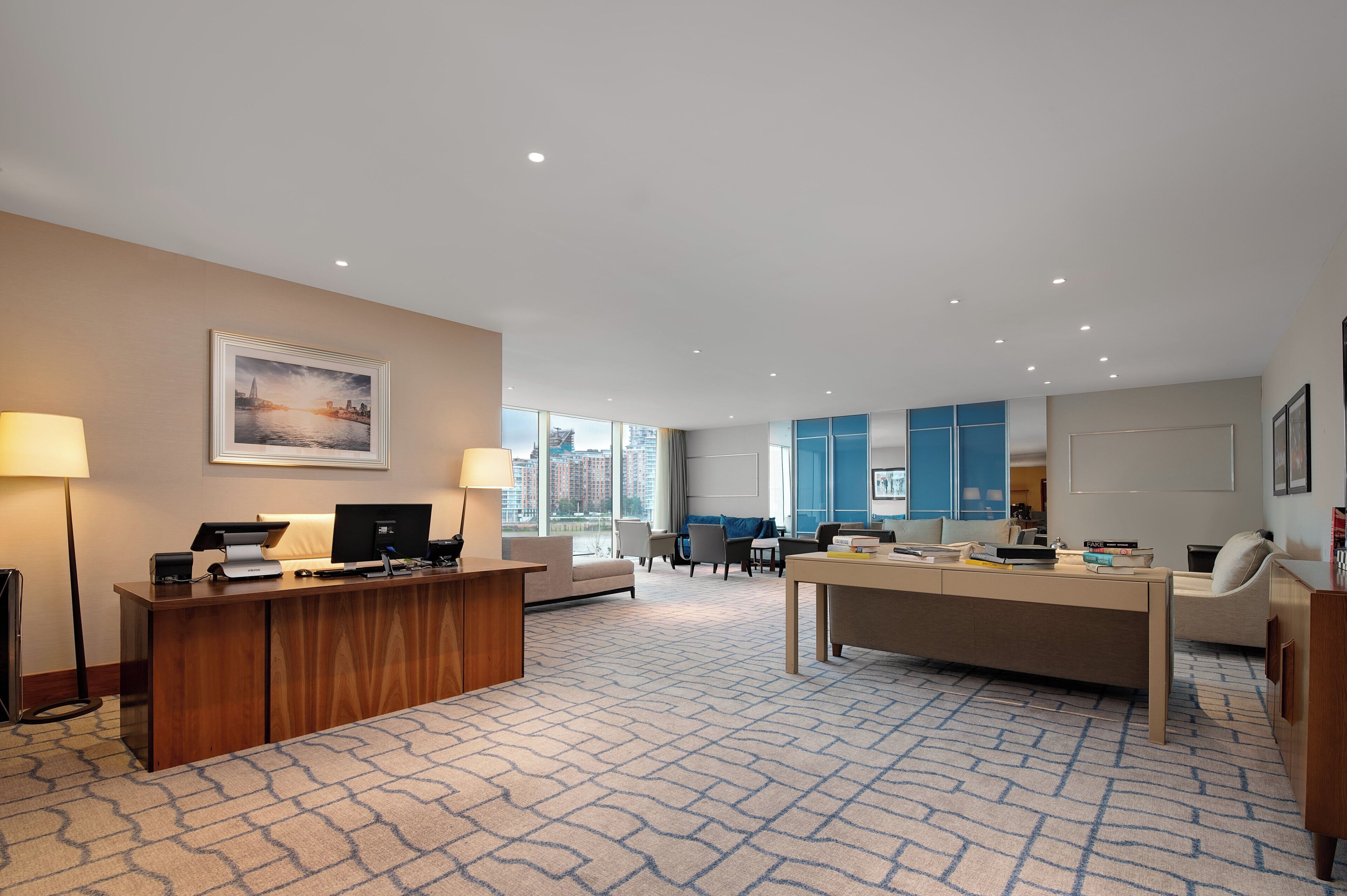 A spacious hotel lobby with a reception desk, seating area, and large windows offering a city view.