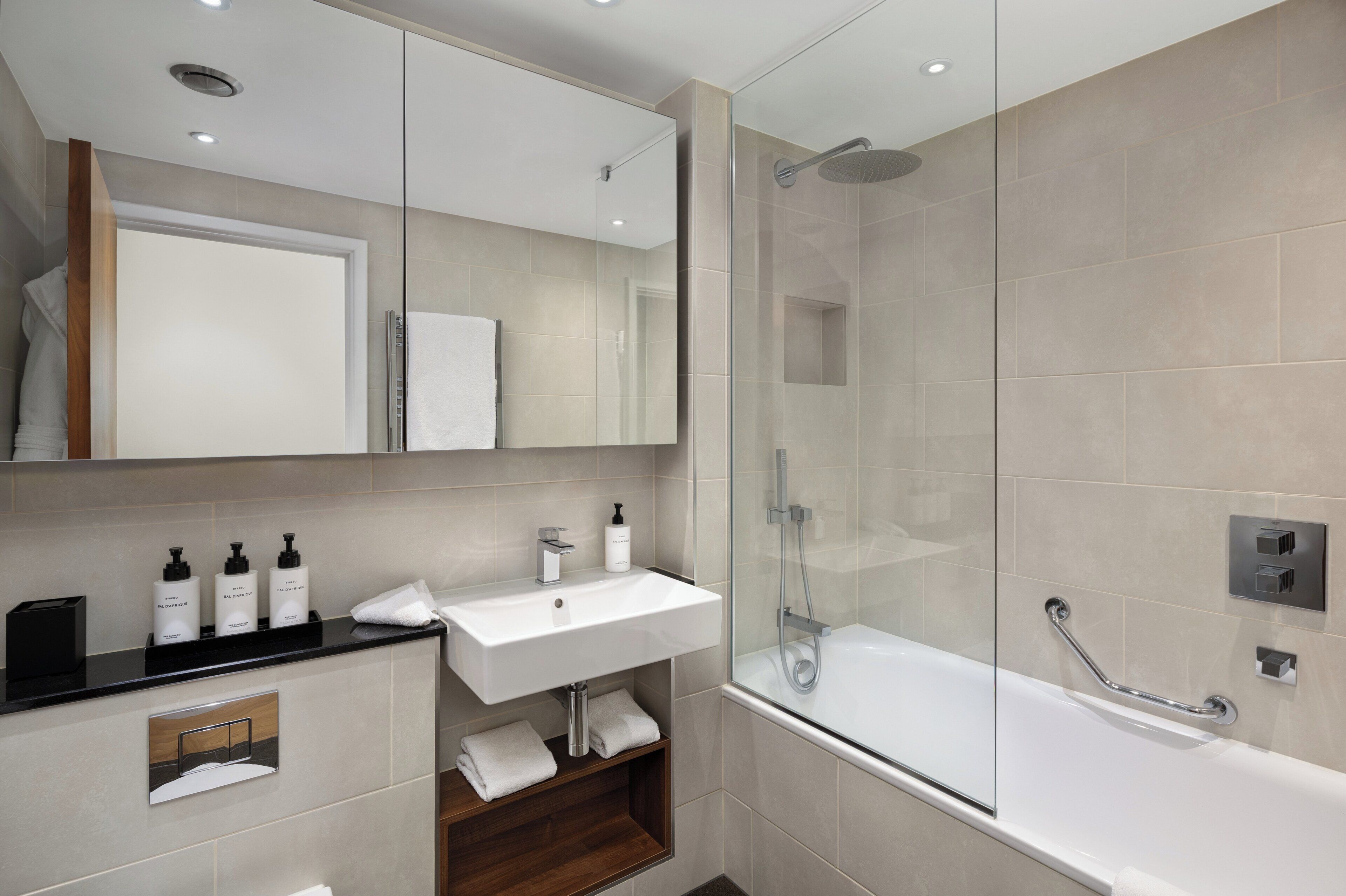 A modern bathroom with a glass-enclosed shower, a white sink, and a mirror above it.