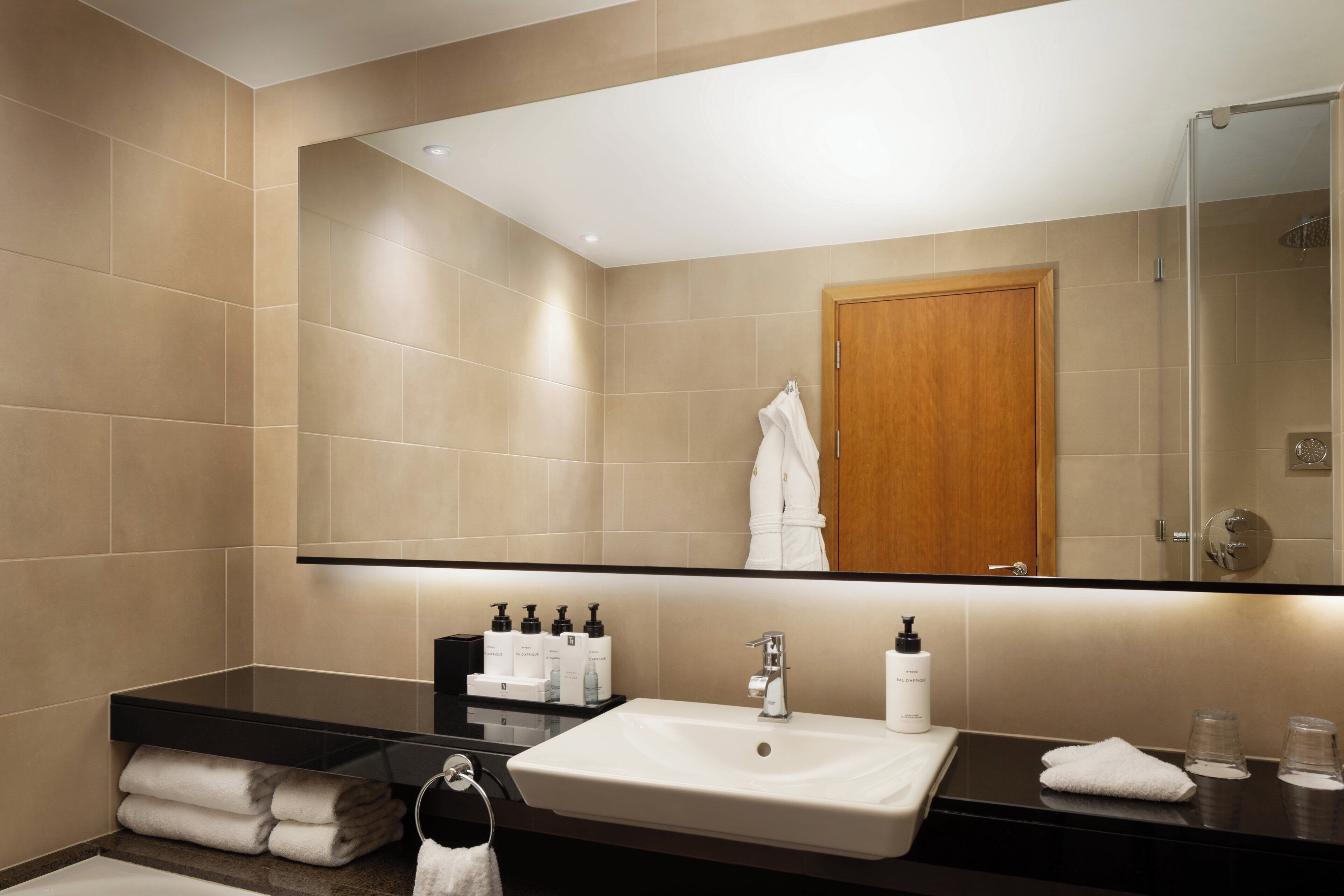 A modern bathroom with a large mirror, a sink, and a shower.