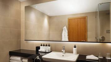 A modern bathroom with a large mirror, a sink, and a shower.