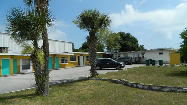 A motel with a yellow exterior, numbered rooms, and a parking area.