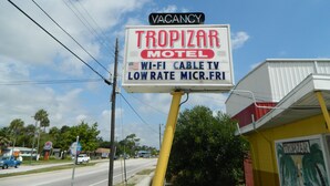 A sign for TropiZar Motel advertising a vacancy, Wi-Fi, cable TV, and low-rate microfridge service.