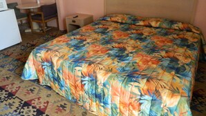 A room with a bed, a small table, a chair, and a nightstand.