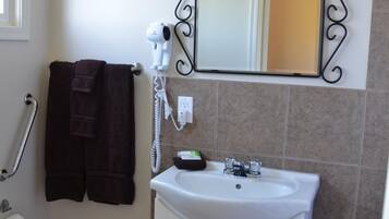 A bathroom with a white sink, a mirror with a decorative frame, a hairdryer, and a towel rack.