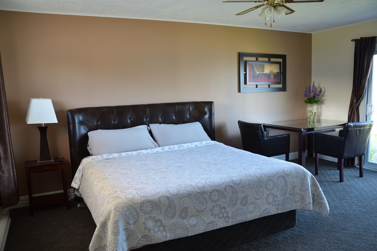 A hotel room with a large bed, a desk, and a chair.