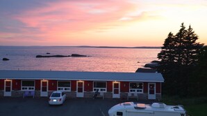 Un edificio rojo con un estacionamiento y vista al océano al atardecer.