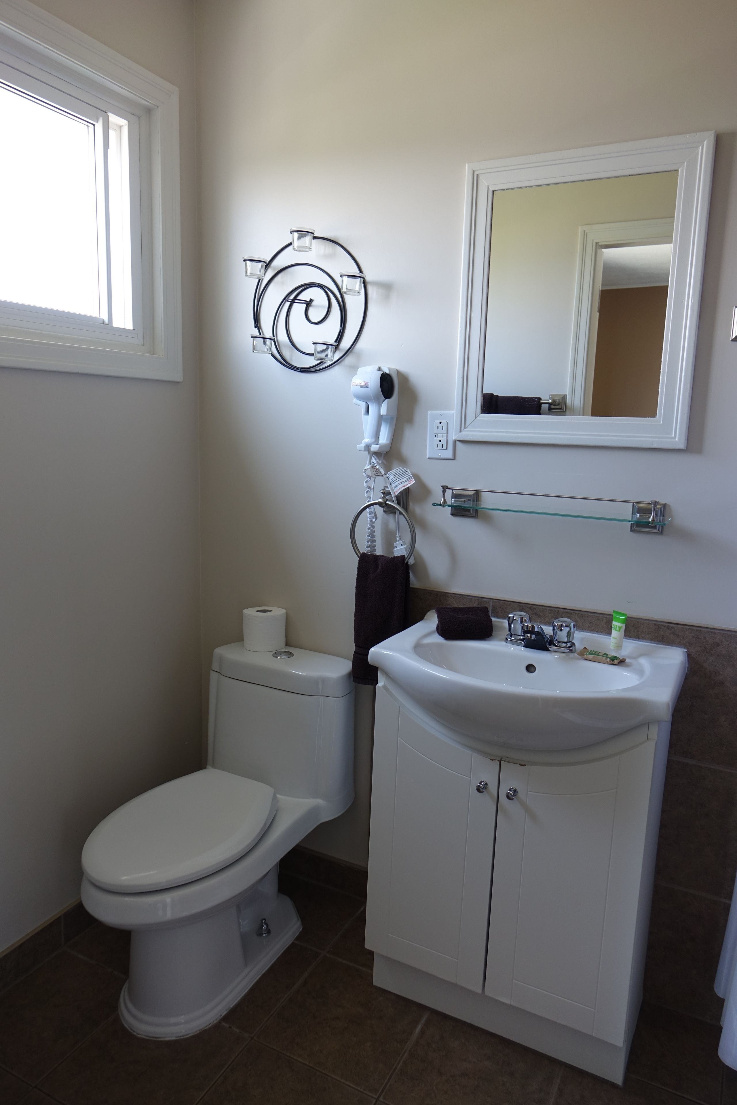 Een badkamer met toilet, wastafel en spiegel.