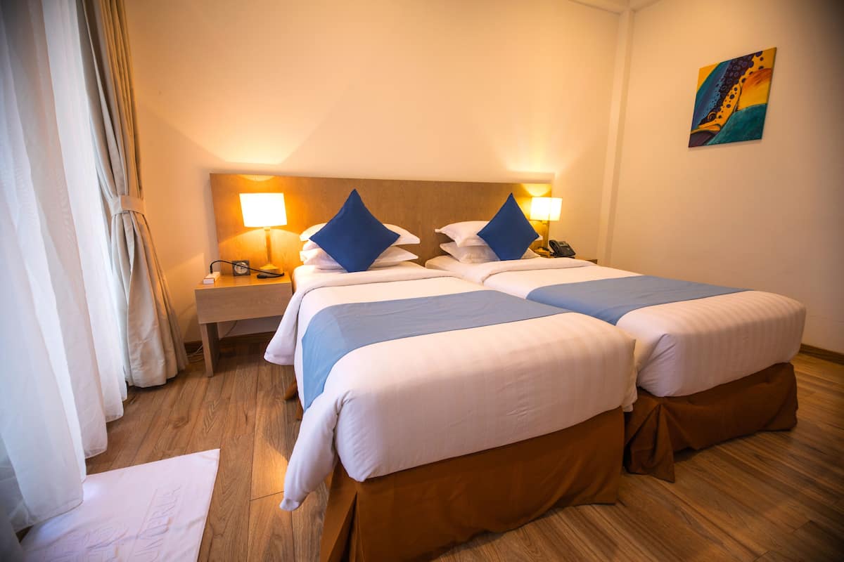 Une chambre d’hôtel avec deux lits, chacun étant équipé d’un oreiller et d’une lampe sur la table de chevet.