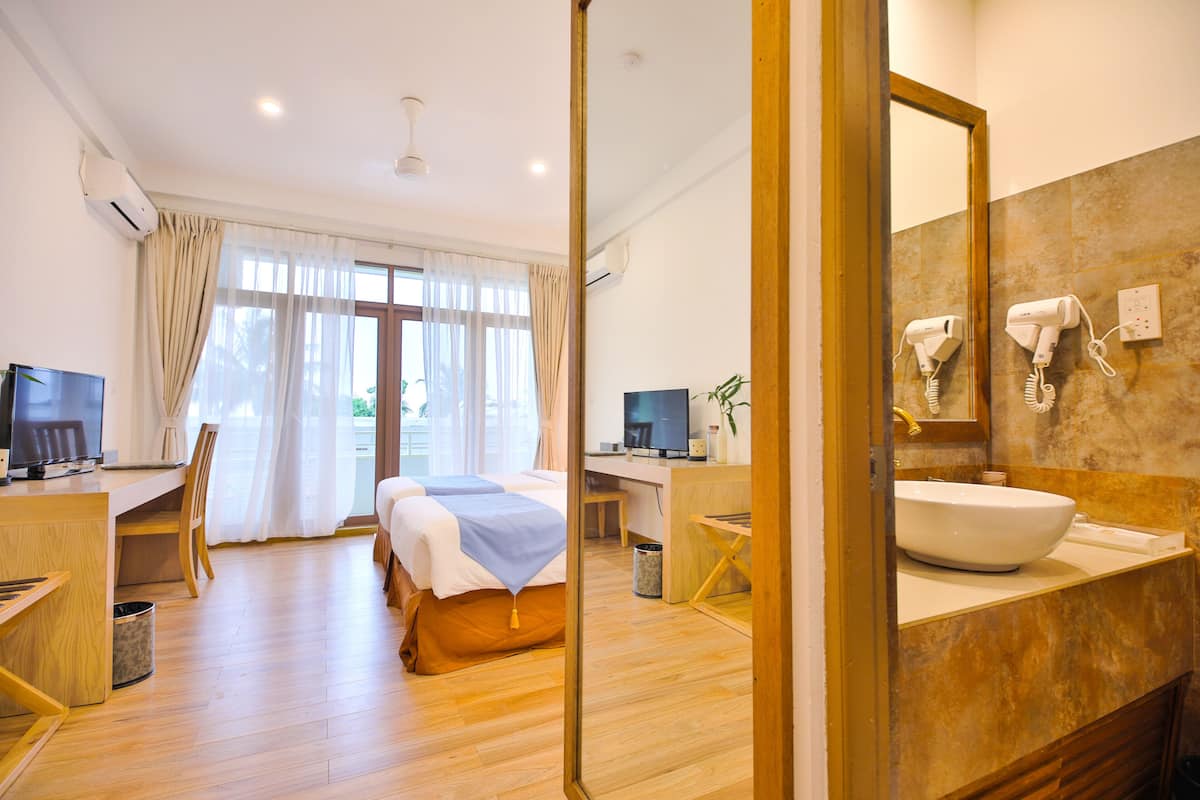 Une chambre d’hôtel équipée d’un lit, d’un bureau, d’un ordinateur et d’une salle de bain avec un lavabo et un miroir.