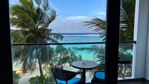 A balcony with a view of the ocean, two chairs, and a small table.