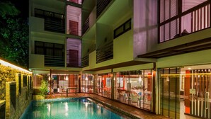 A multi-level hotel with a swimming pool, outdoor seating, and a restaurant.