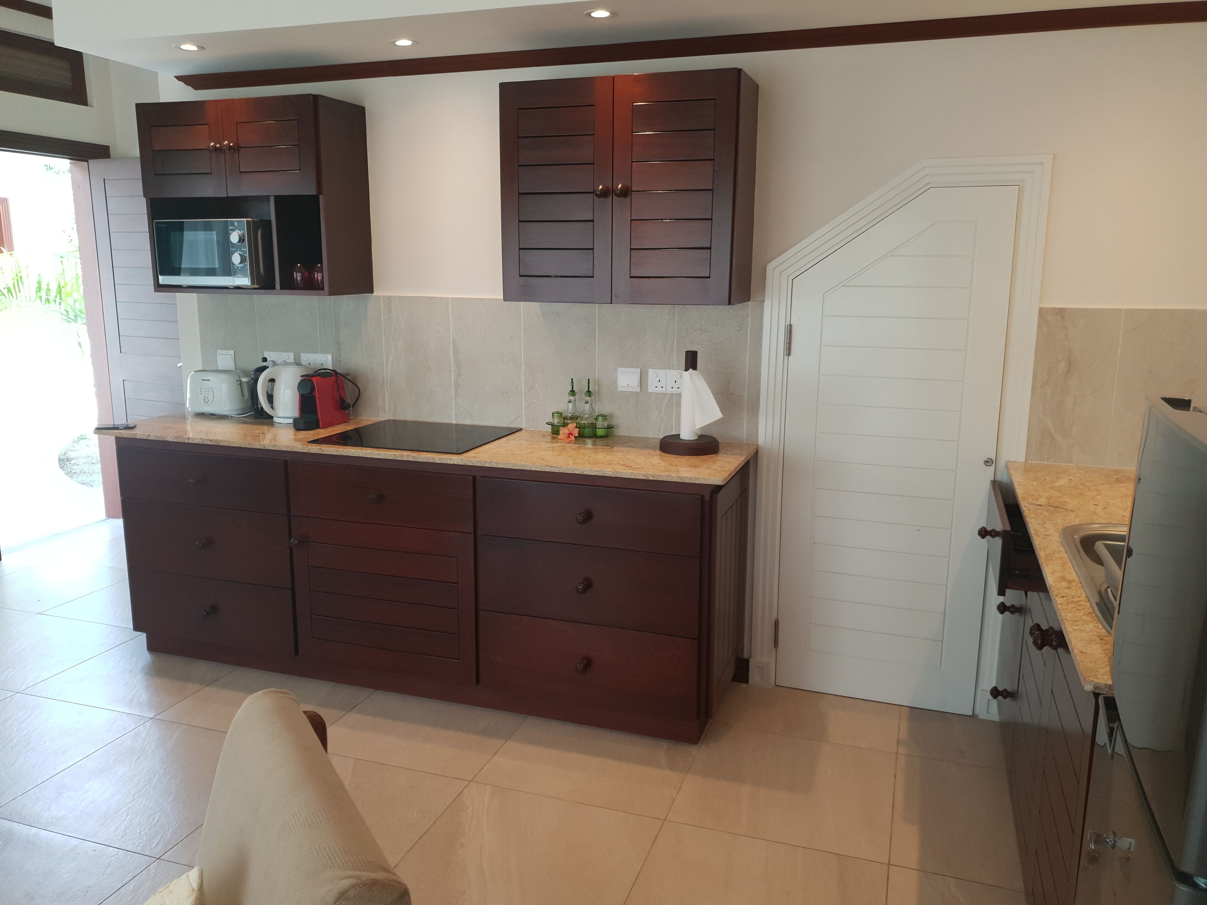 A modern kitchen with dark wooden cabinets, a built-in microwave, and a large countertop.