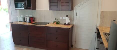 A modern kitchen with dark wooden cabinets, a built-in microwave, and a large countertop.