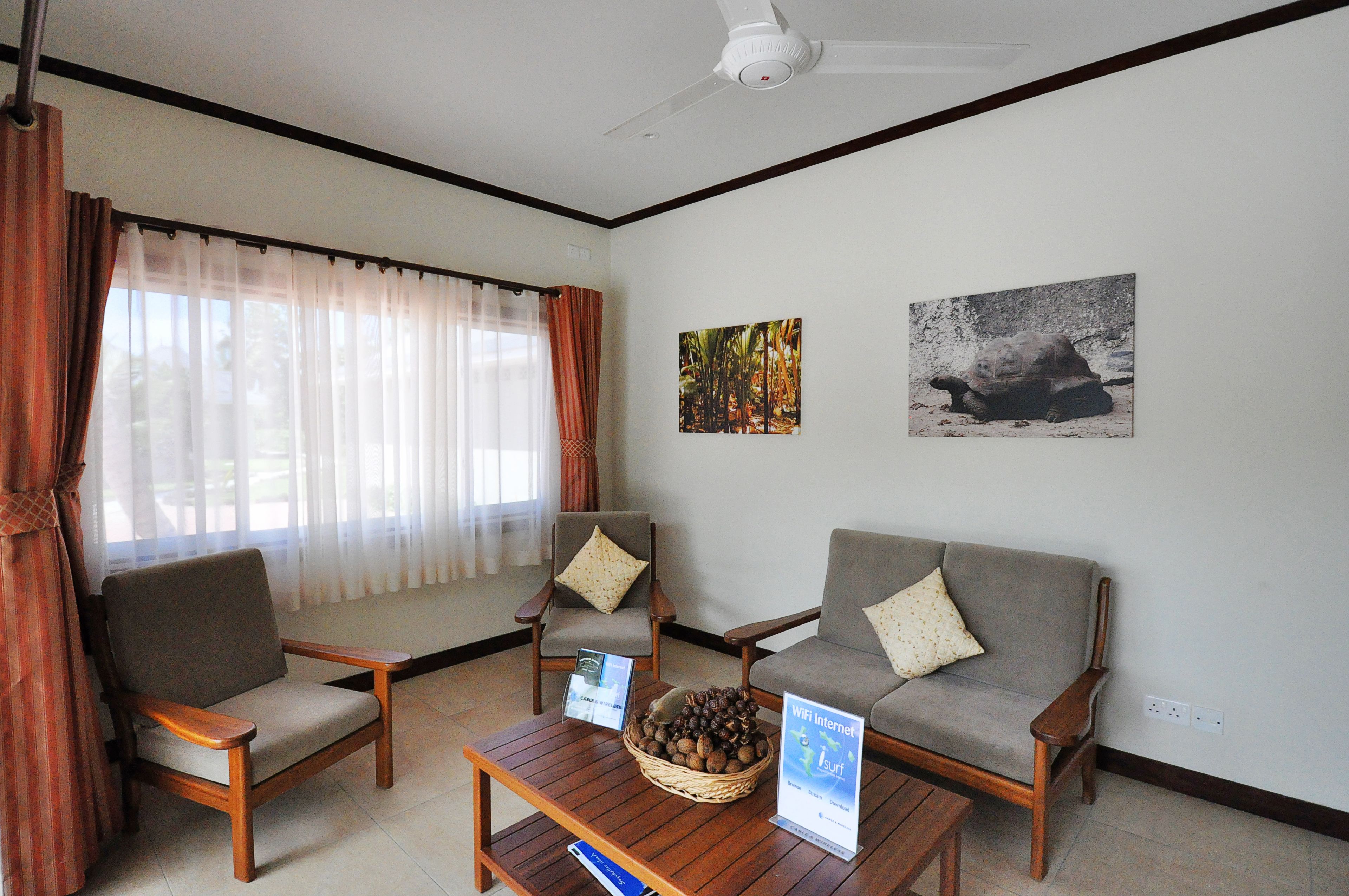 A room with two sofas, a wooden coffee table with a basket, and a ceiling fan.