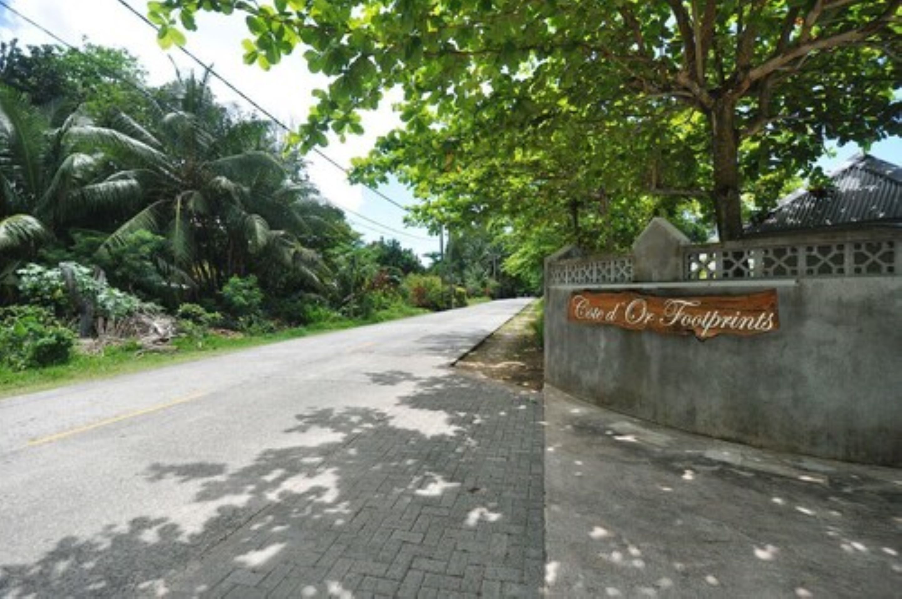 A paved pathway beside a road with a sign reading "Cost Of Footprints."