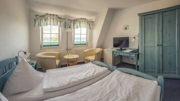 A bedroom with a bed, two chairs, a desk, a television, and a wardrobe.