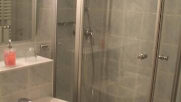 Un baño con ducha de vidrio, lavamanos y espejo.