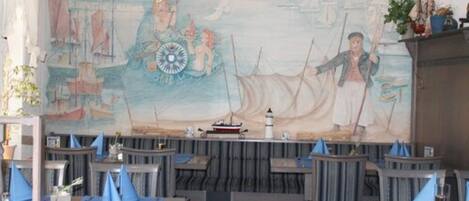 A restaurant with nautical-themed murals, wooden tables, and blue napkin holders.