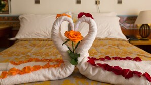 A bed with a decorative towel arrangement in the shape of a heart, featuring orange and red flowers. - Hotel Sindibad (Agadir)